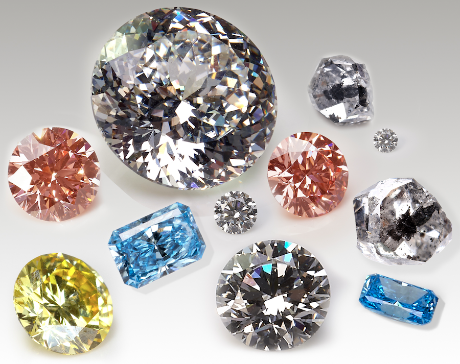 Colored lab grown diamonds in pink, yellow, and blue are shown in various cuts of radiant cut and brilliant round, alongside a round Portuguese cut white lab diamond and salt and pepper Canadian mined diamond